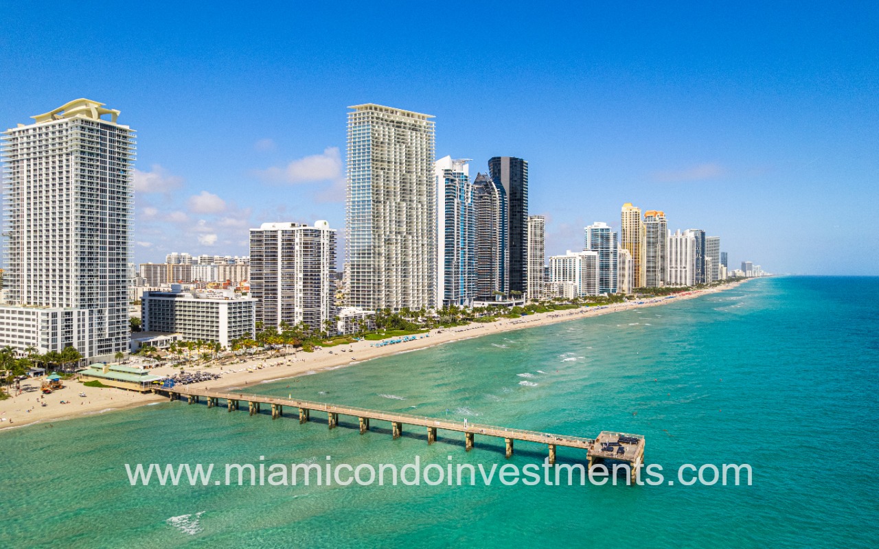 Jade Beach condo building amongst buildings on beach shoreline wide view