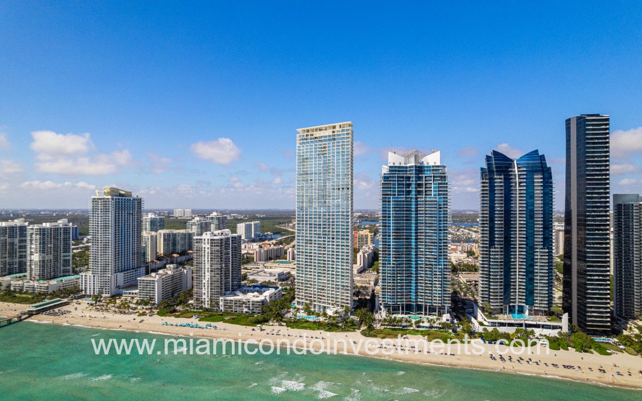 Jade Signature drone facing condo building and beach shoreline wide view