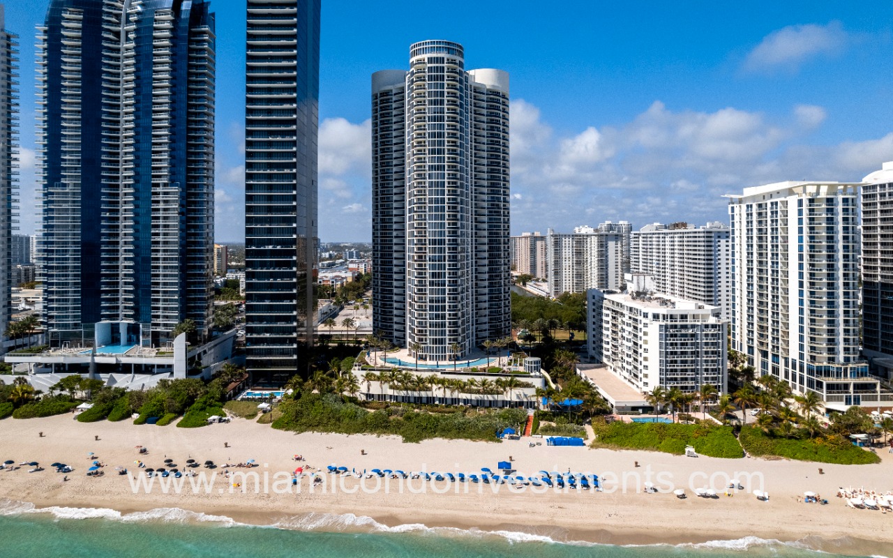 Ocean Four drone directly facing building and beach from ocean closeup