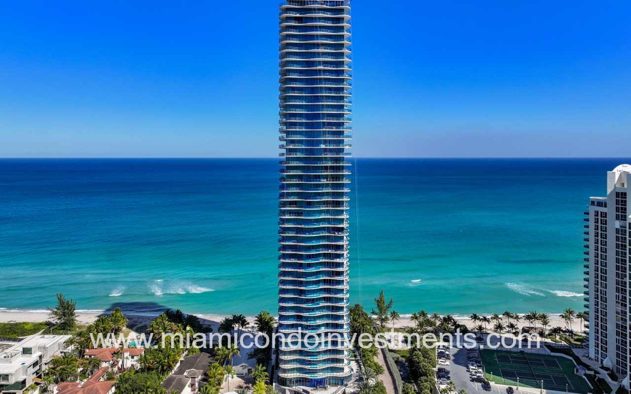 Ragalia drone view closeup facing condo building front exterior with blue ocean backdrop