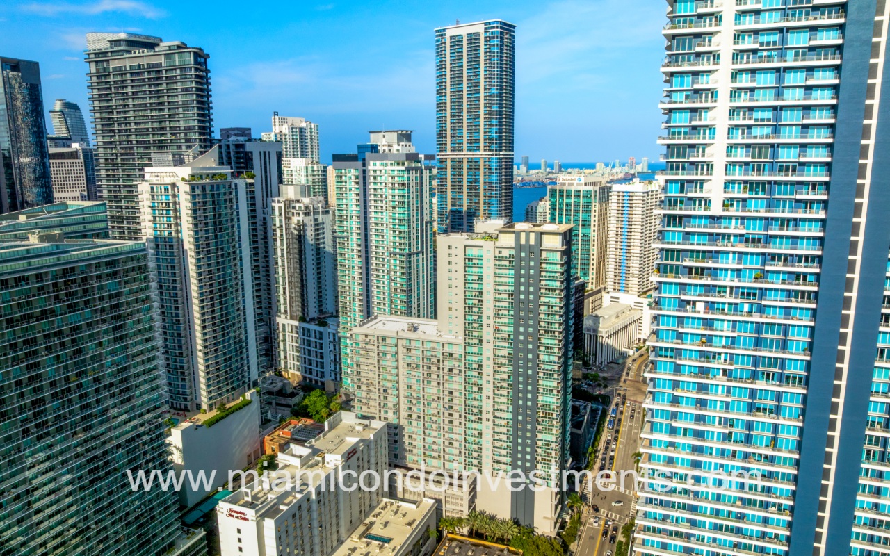 Vue drone view of condo building and city buildings surrounding