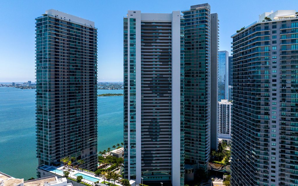 Paraiso Bay drone facing front of condo building exterior with bay view backdrop