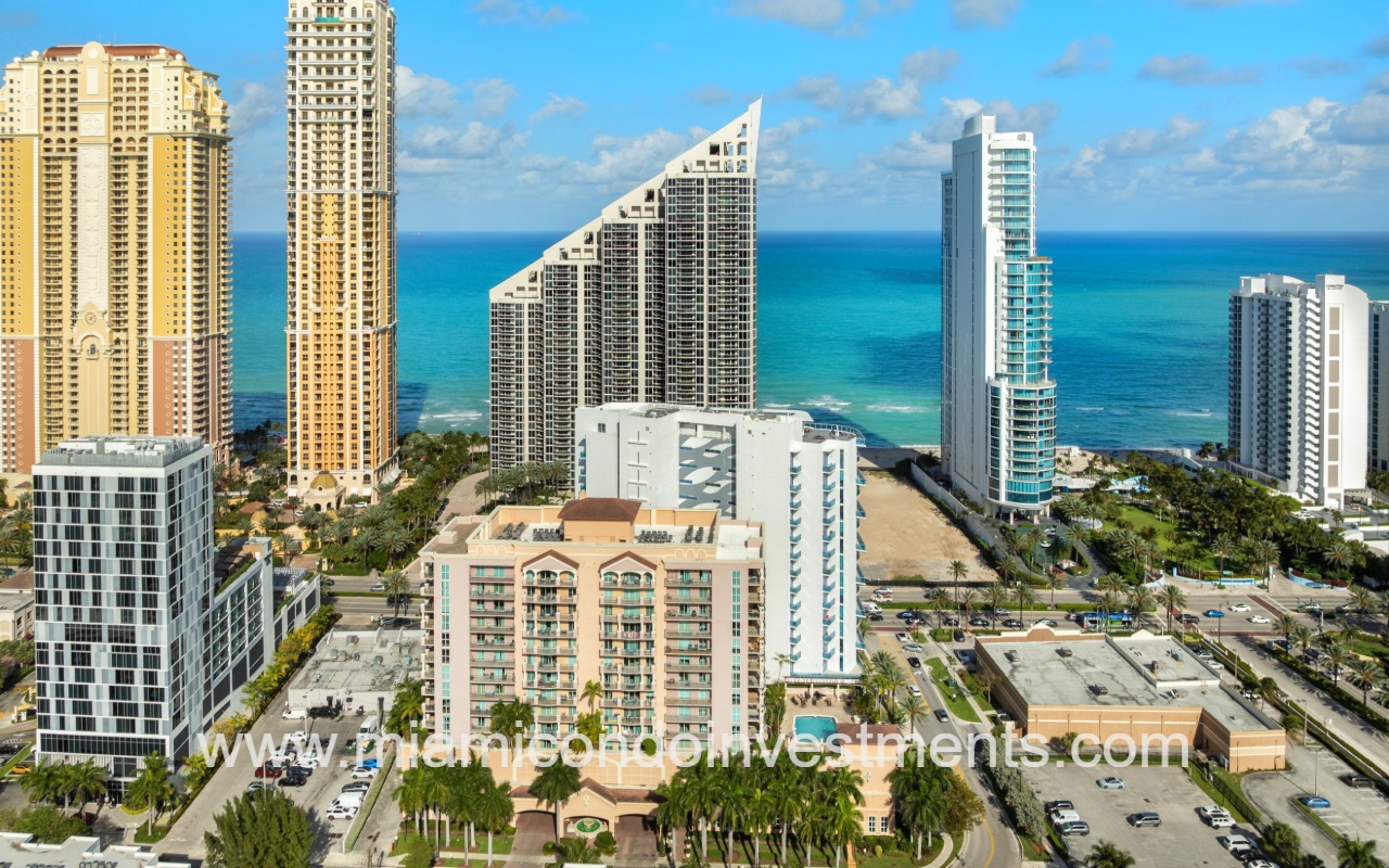 Aurora drone view of side of condo building from sky with buildings and ocean in background