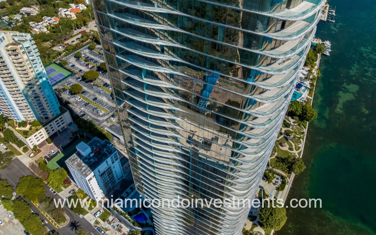 UNA Residences condominium building closeup aerial view of tall glass tower with a curved facade