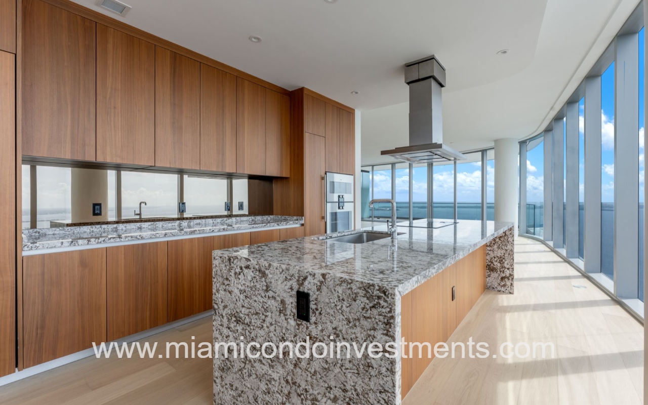 UNA Residences condominium building 4-bedroom closeup modern kitchen with granite island, wooden cabinets, and floor-to-ceiling windows overlooking Biscayne Bay