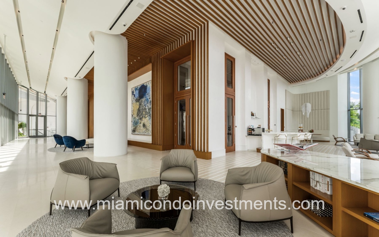 UNA Residences condominium building luxurious modern hotel lobby with circular seating, beige chairs, and a wooden slatted ceiling.