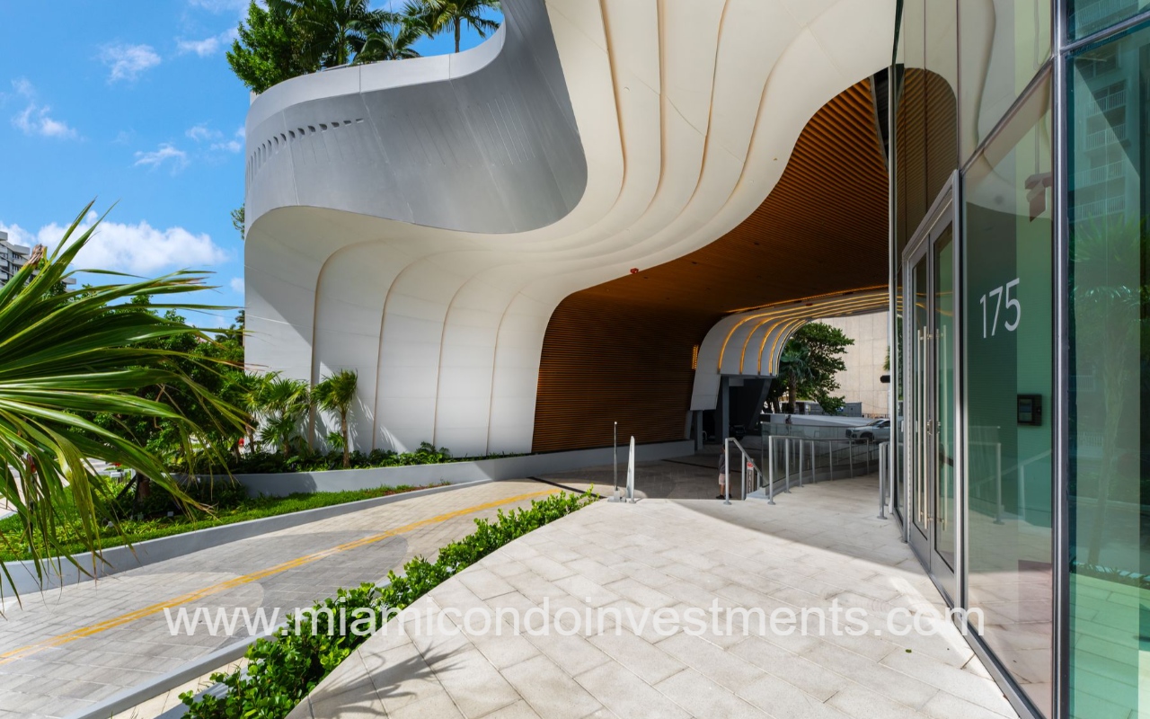 UNA Residences condominium building modern curved white exterior with a wood-lined entrance and glass doors
