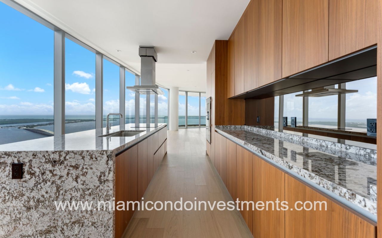 UNA Residences condominium building 5-bedroom kitchen with granite countertops island stove top surrounded by floor-to-ceiling glass with natural light