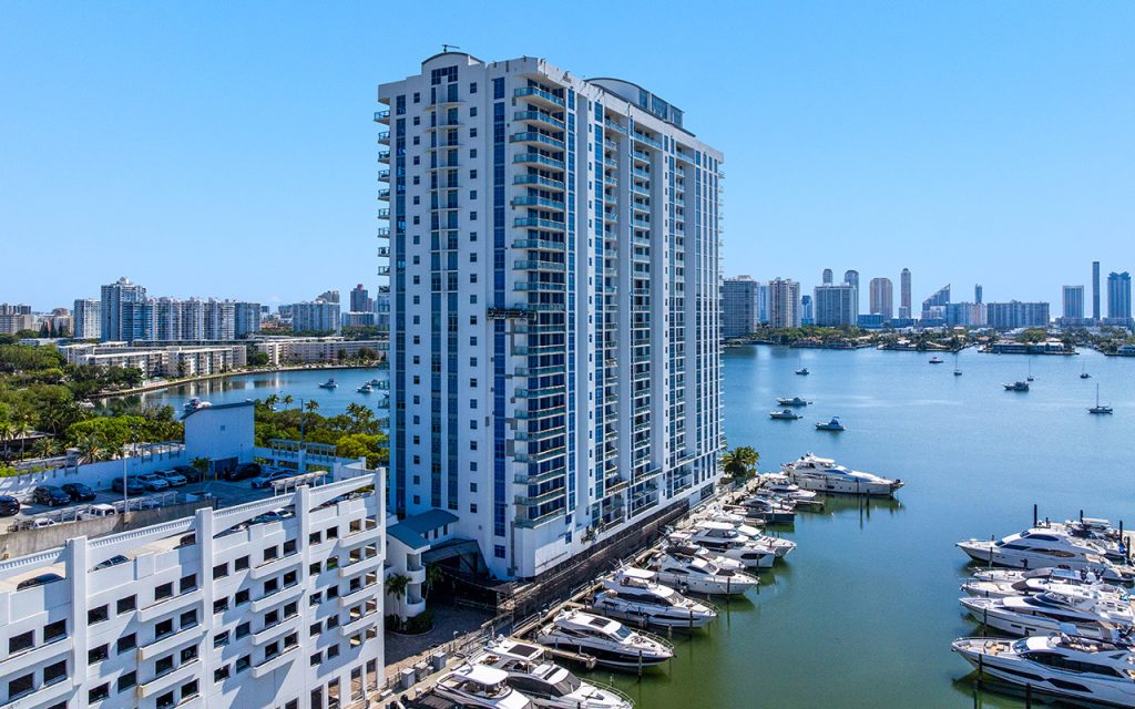 Marina Palms North drone facing northward with condo building and yachts parked